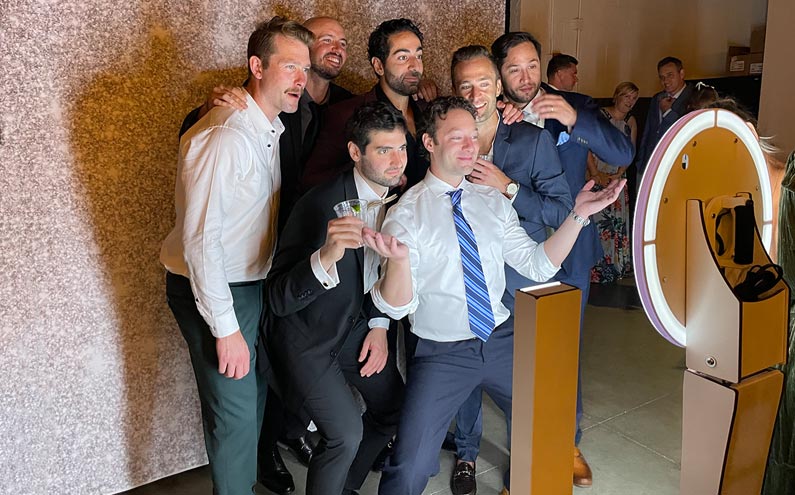 Group shot of all men posing in front of a Photo Booth.