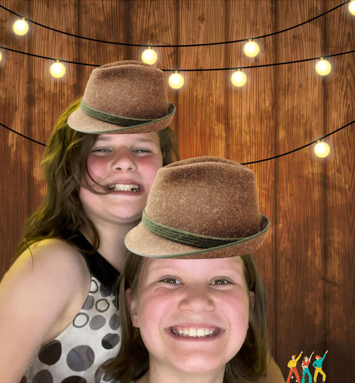 Two young girls wearing brown hats in front of virtual background