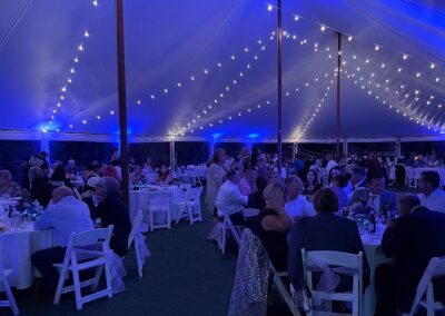 Ashley & EJ's indoor wedding tent illuminated with blue uprights with guests seated for dinner