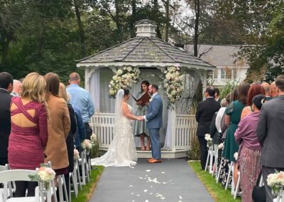 Eric & Alex standing in front of a Gazebo about to deliver their vows