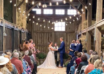 Rebecca & Dusty standing in horse barn with officiant stating their wedding vows