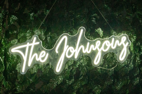 A custom neon sign glowing against a green back drop